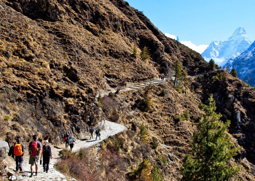 Hikers walking along a narrow path in the Himalayas to Everest Base Camp