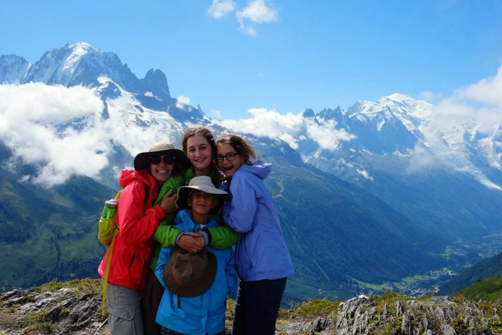 Friends cuddle together for a photograph in front of the Mont Blanc Massif