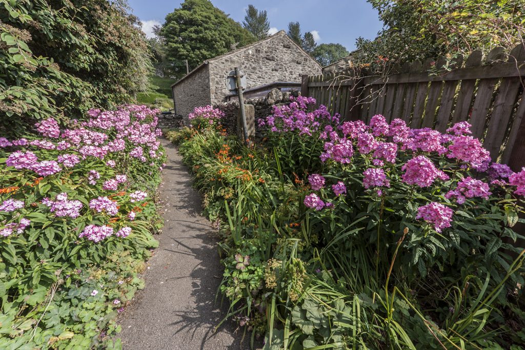 Pink and purple flowers line the path leading to the Yorkshire town of Grassington