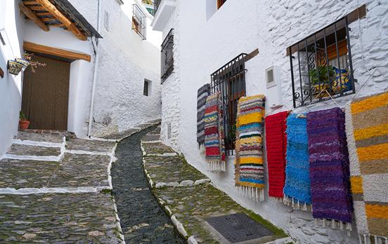 Rainbow coloured rugs lining Capileira