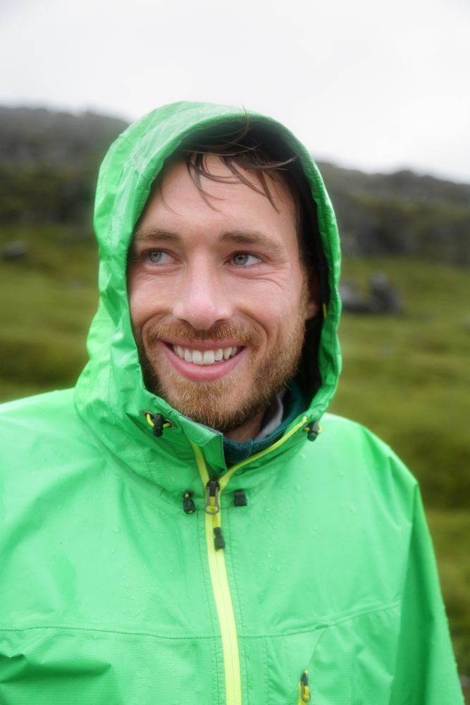 wet man in waterproof jacket smiles