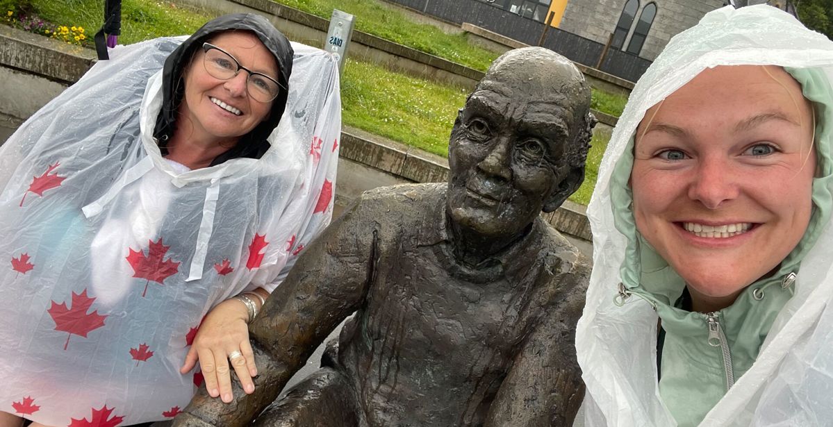 Two hikers take a photo with the sore feet statue West Highland Way