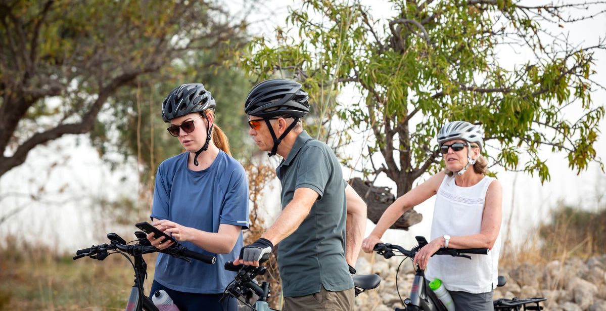 Three cyclists check their Macs Adventure travel app