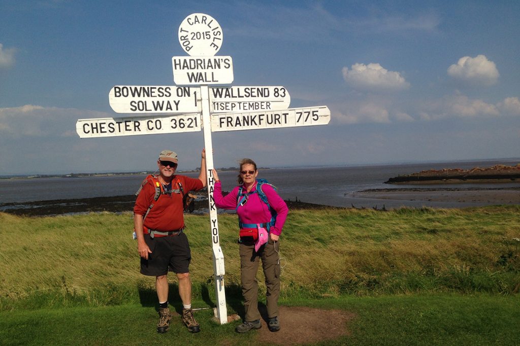 Two hikers under a sign on the Hadrian's Wall Path